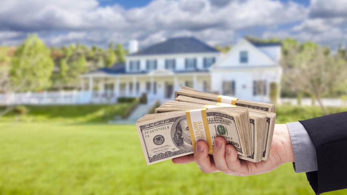 man holding cash in front of a house